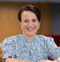 Photo of Paula, a woman with dark hair wearing a black and white blouse