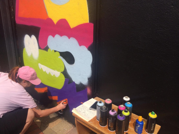 Pinky works on one of her art works using a spray can